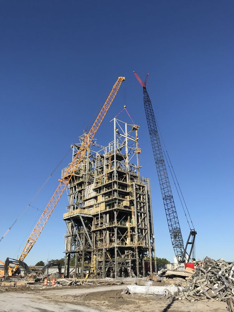 Cranes surrounding an industrial concrete structure during demolition