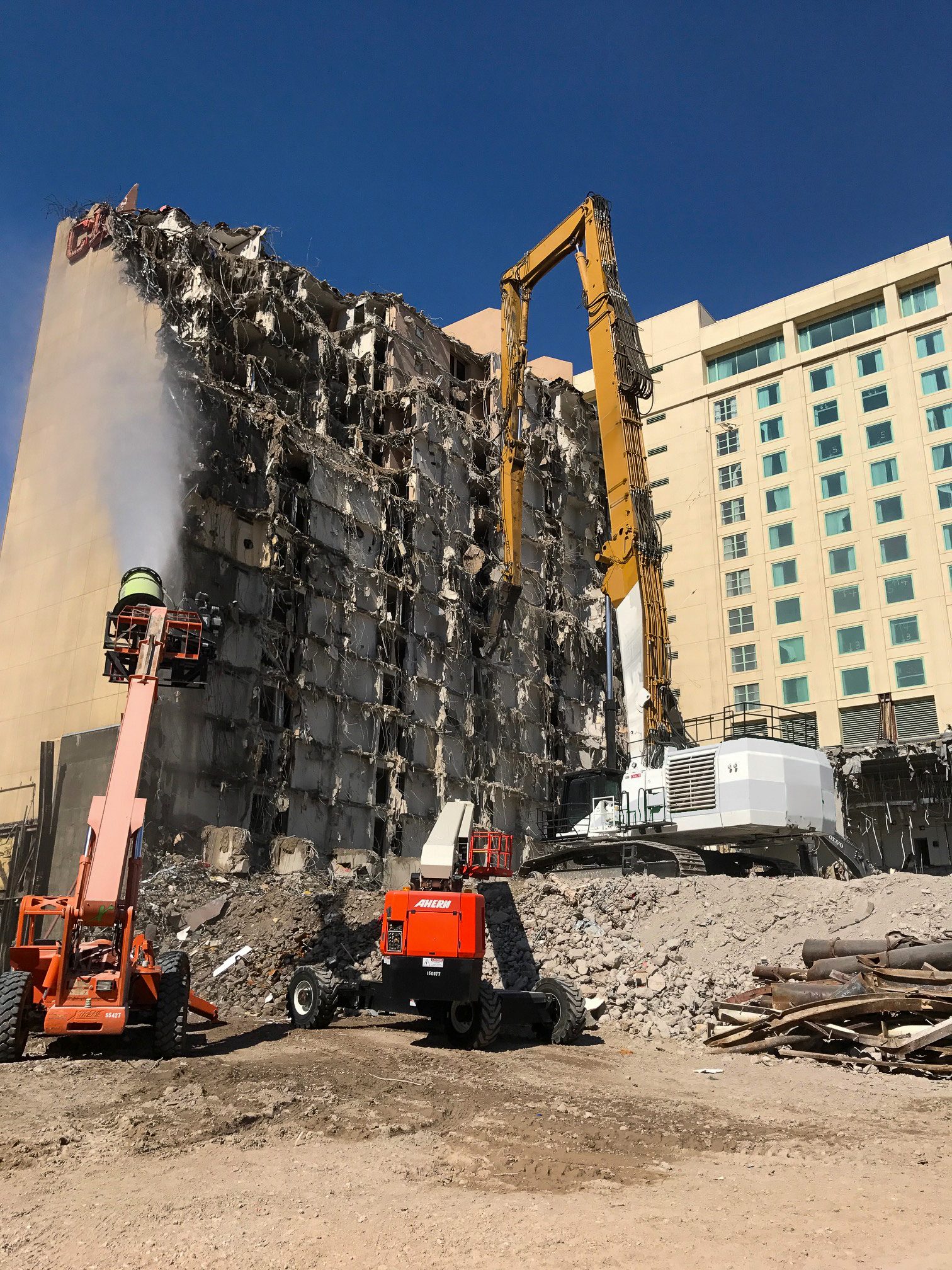 High-reach excavator taking down the Las Vegas Club hotel tower floor by floor beside a neighboring hotel